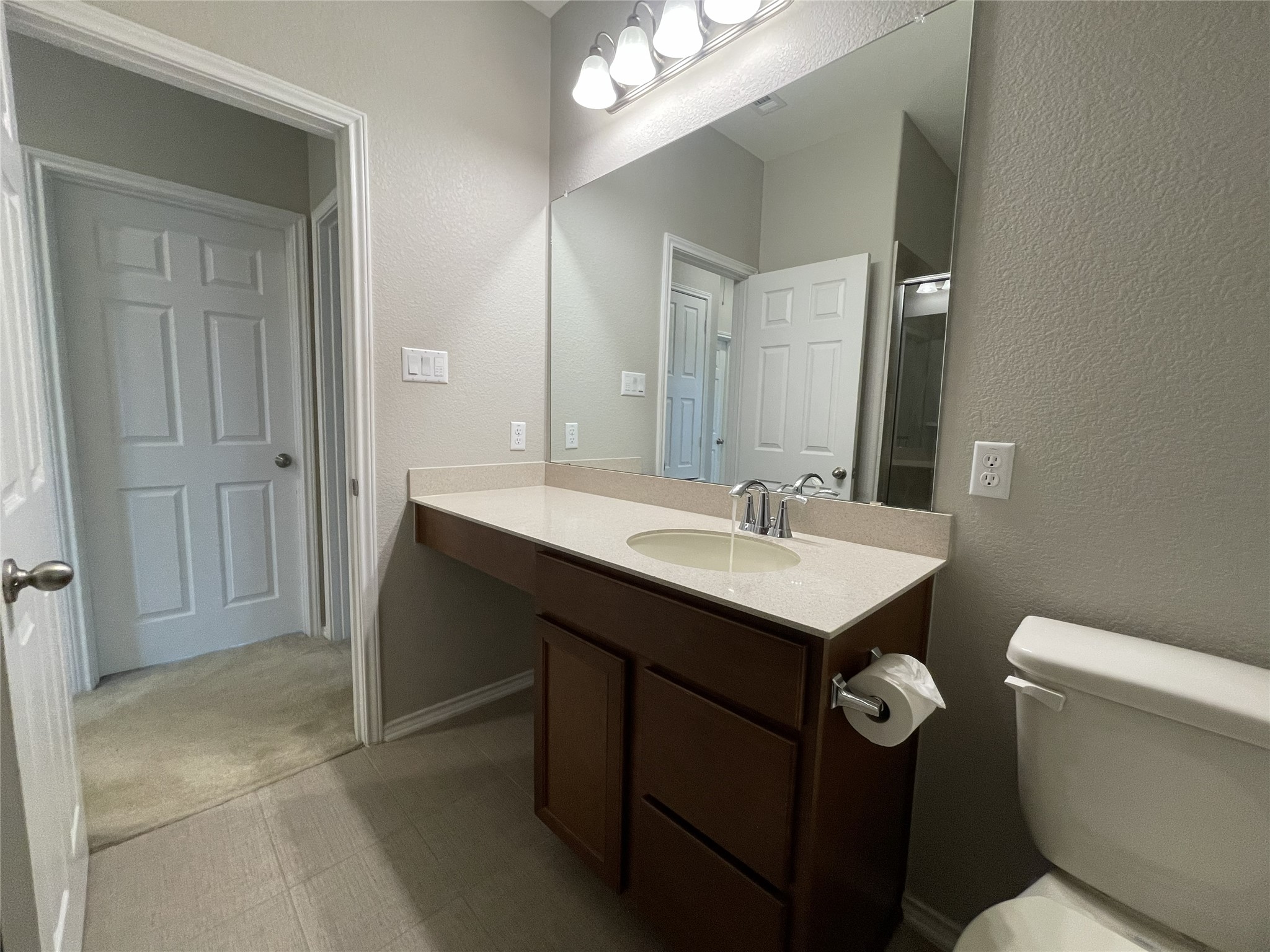 2471 Sunrise Road, Unit 62 Round Rock, TX 78664 - Photo 24 of 28 Bathroom featuring a textured wall, vanity, and light carpet