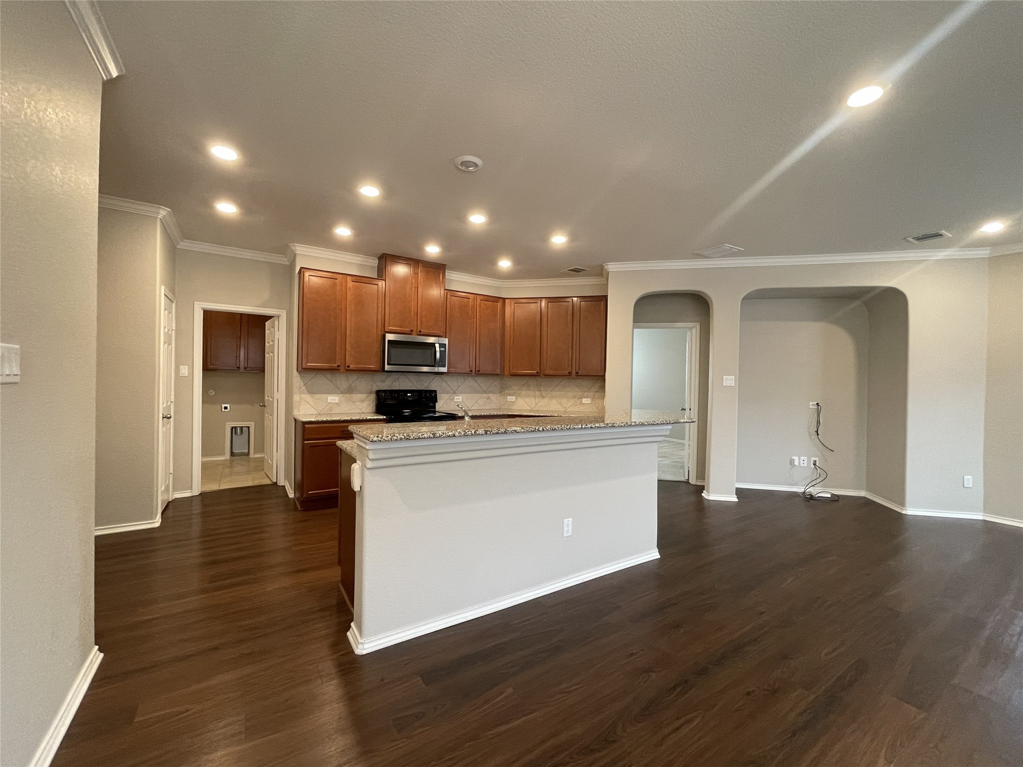 2471 Sunrise Road, Unit 62 Round Rock, TX 78664 - Photo 9 of 28 Kitchen featuring wood finish cabinetry, arched walkways, crown molding, dark wood-style flooring, and stainless steel microwave