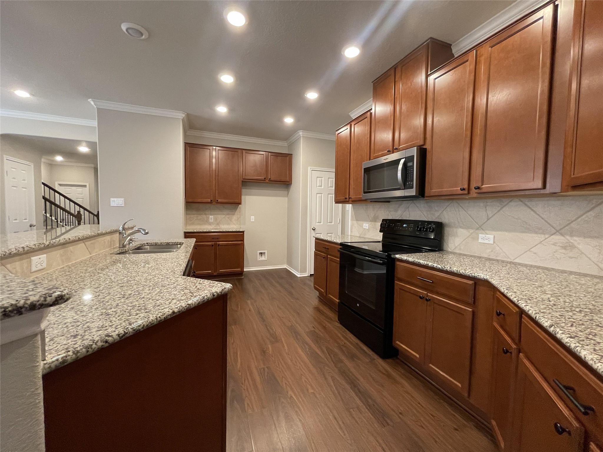 2471 Sunrise Road, Unit 62 Round Rock, TX 78664 - Photo 10 of 28 Kitchen with black electric range oven, dark wood-style flooring, light stone counters, stainless steel microwave, and crown molding