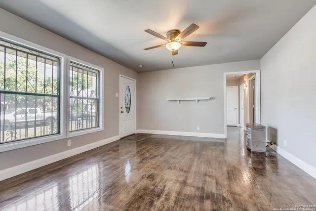 a view of an empty room with a window and wooden floor
