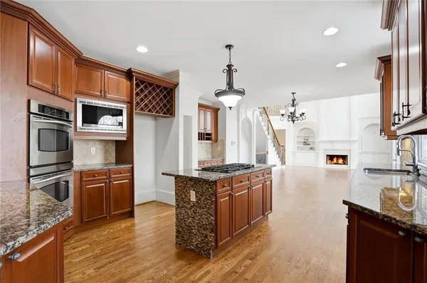 a large kitchen with stainless steel appliances granite countertop a refrigerator a stove top oven a sink dishwasher and wooden floor