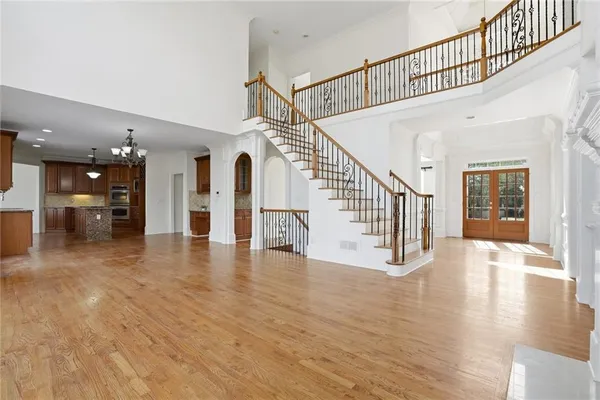 an empty room with wooden floor chandelier and windows