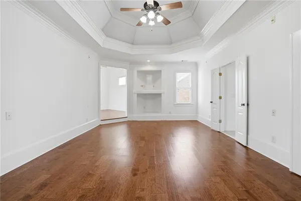an empty room with a chandelier fan and windows