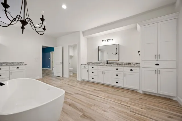 a large white kitchen with a white island a stove a sink and a large mirror