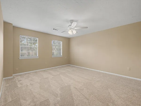 an empty room with windows and ceiling fan