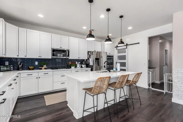 a large kitchen with kitchen island granite countertop lots of white cabinets stainless steel appliances and dining table