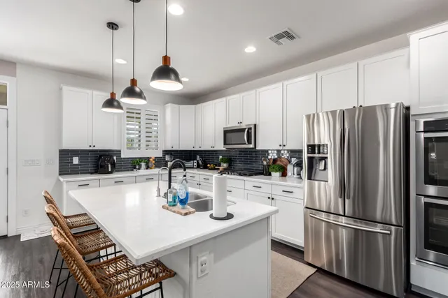 a kitchen with stainless steel appliances a stove a refrigerator a sink a stove a dining table and chairs