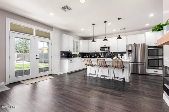 a kitchen with stainless steel appliances kitchen island granite countertop a refrigerator a stove a oven a large island with wooden floor and cabinets