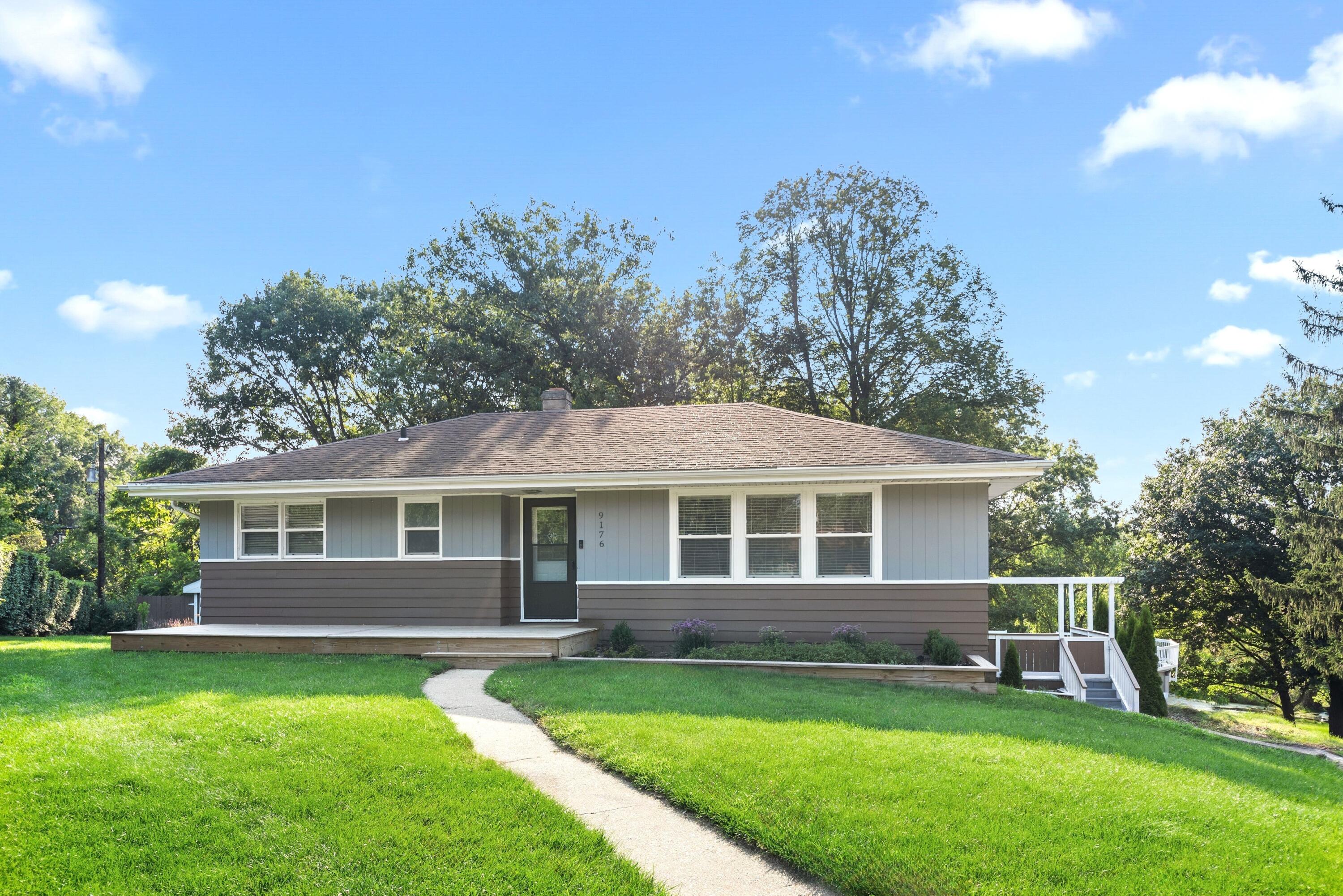 a front view of a house with a yard and trees