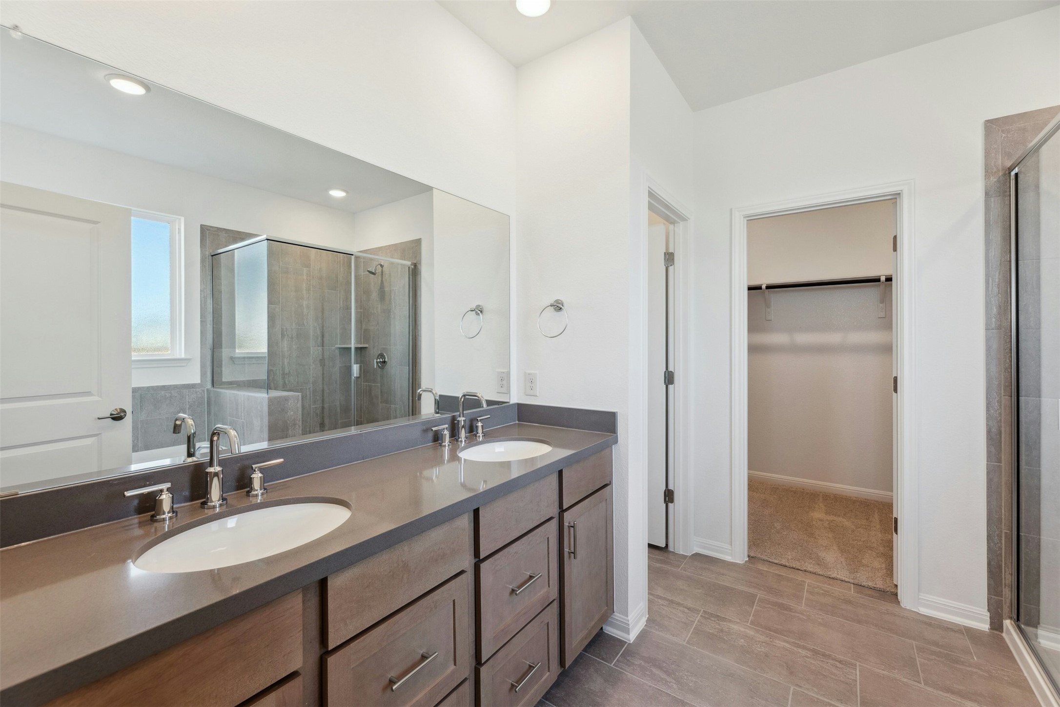 2001 Wynn Road Hutto, TX 78634 - Photo 15 of 39 Dual vanities with sleek countertops complement the generous walk-in shower and nearby closet access.