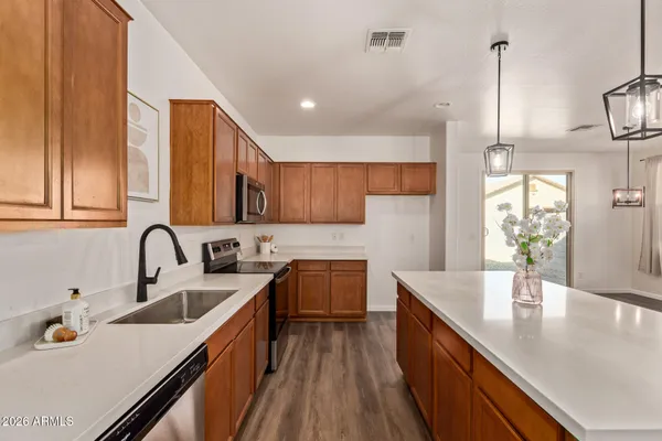 a kitchen with kitchen island granite countertop a sink a counter space appliances and cabinets