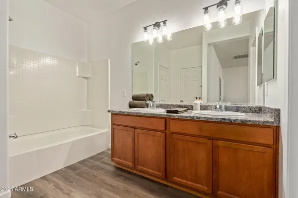 a bathroom with a granite countertop sink a mirror and a bathtub