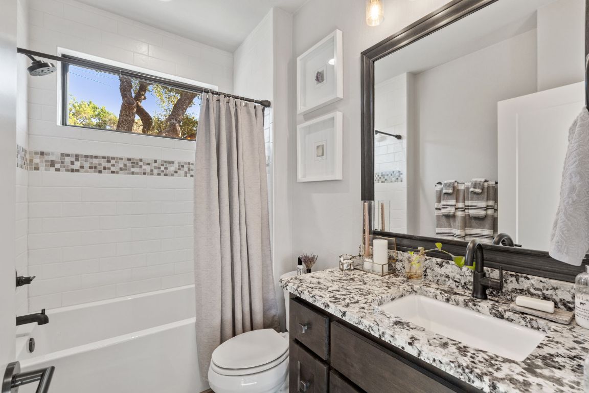 418 Summit Ridge Drive North Lago Vista, TX 78645 - Photo 10 of 40 a bathroom with a granite countertop sink a toilet a mirror a vanity a bath tub and shower