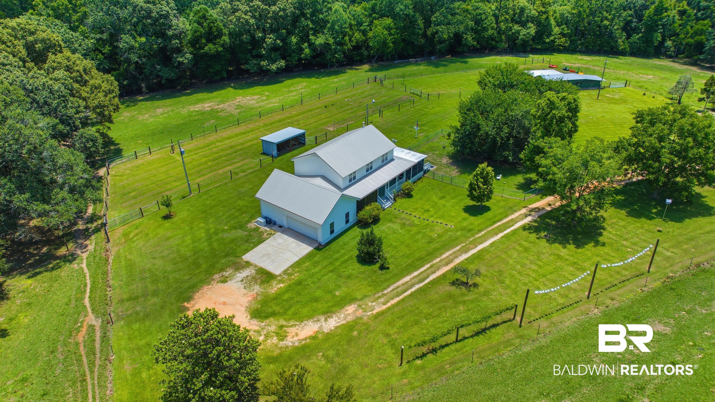15855 Calvin Richerson Road Bay Minette, AL 36507 - Photo 10 of 83 Spacious property featuring a light-colored two-story residence with a metal roof, attached two-car garage, and an expansive covered porch