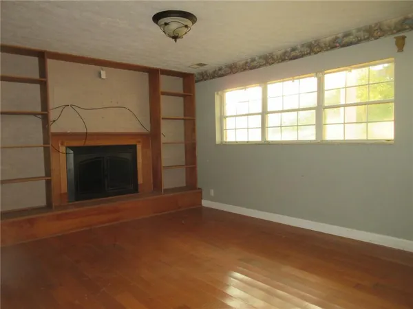 an empty room with windows and fireplace