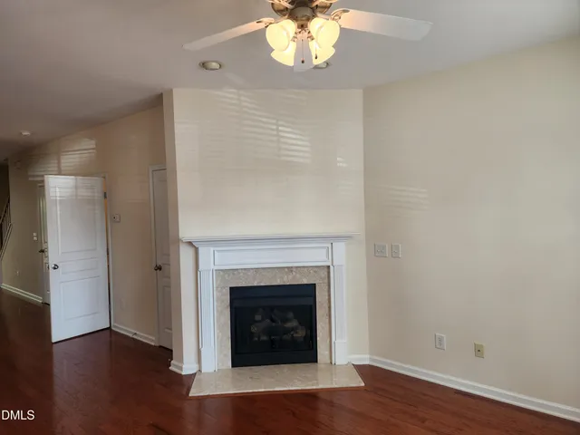 a view of an empty room with wooden floor and a fireplace