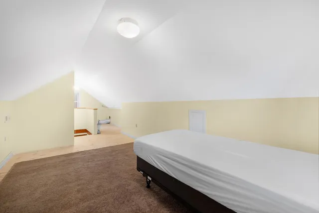 a spacious bedroom with a bed and a lamp on the dresser