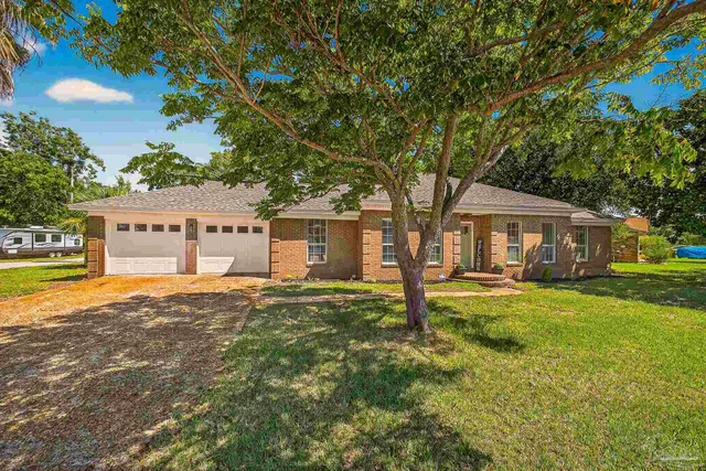 a front view of a house with yard tree and outdoor seating