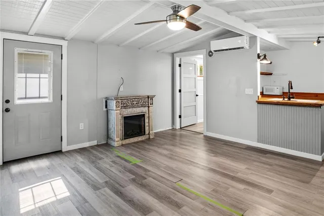 a view of a livingroom with wooden floor a ceiling fan a fireplace and windows