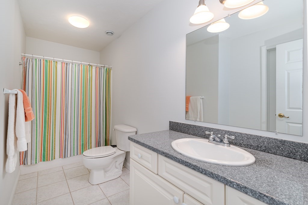 23 Gold Leaf Lane, Unit 23 Mashpee, MA 02649 - Photo 23 of 32 a bathroom with a granite countertop sink and a mirror with toilet