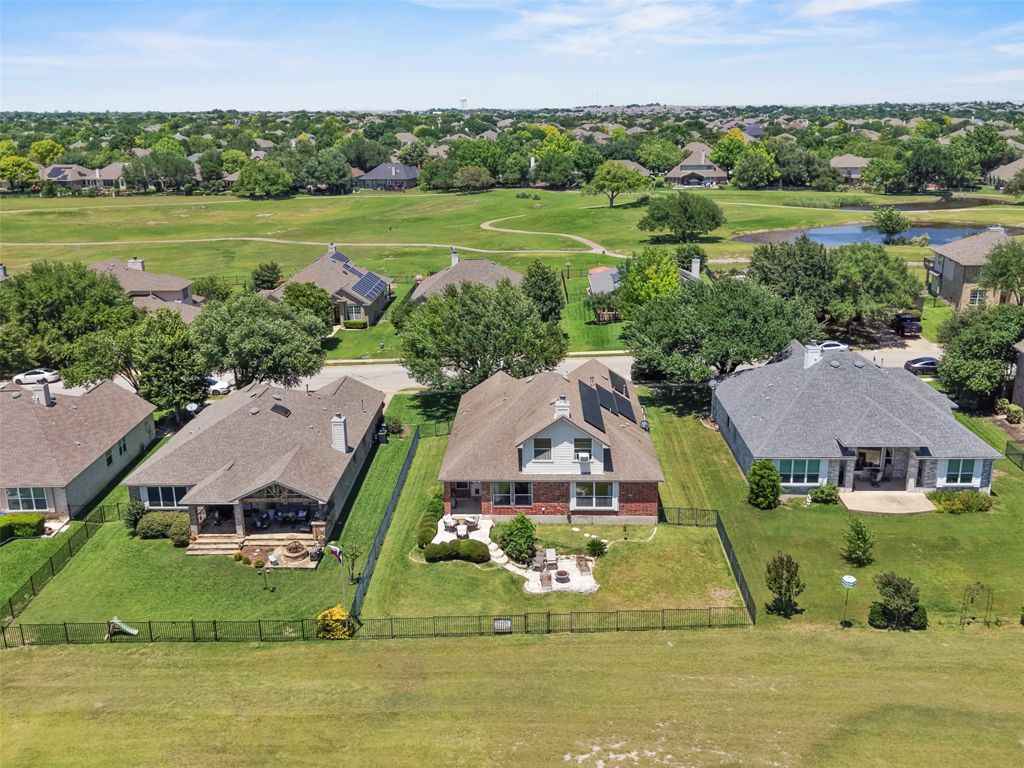 2521 Amen Corner Road Pflugerville, TX 78660 - Photo 38 of 40 Rear exterior featuring an expansive yard with a black metal fence, a covered patio, and a stone patio