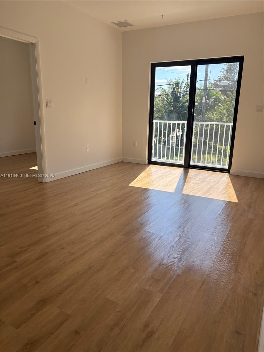 85 Northeast 55th Street, Unit 7 Miami, FL 33137 - Photo 9 of 13 a view of an empty room with wooden floor and a window