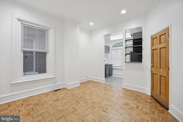a view of empty room with kitchen and windows