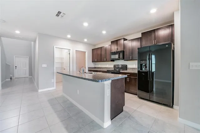 a kitchen with stainless steel appliances granite countertop a refrigerator and a stove top oven