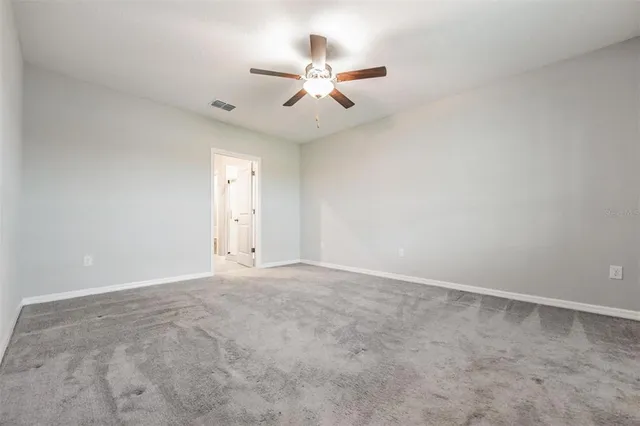 an empty room with chandelier fan and window
