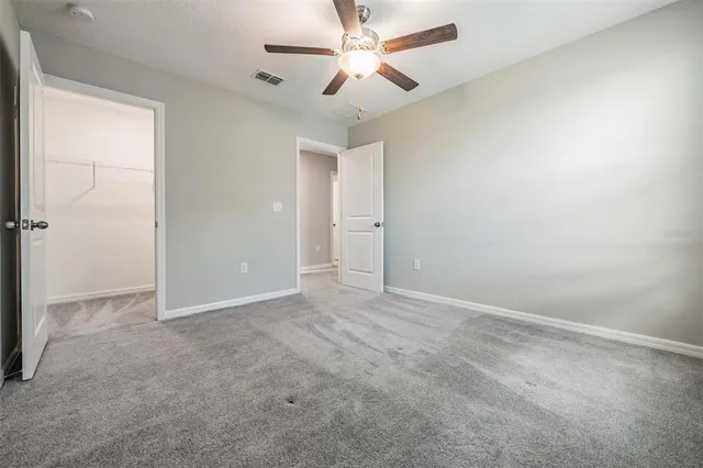 an empty room with closet and a ceiling fan