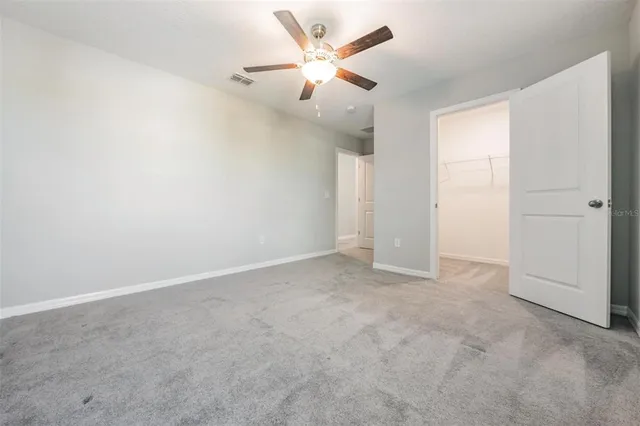 an empty room with a ceiling fan and a window