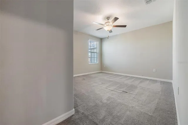 a view of an empty room with chandelier fan