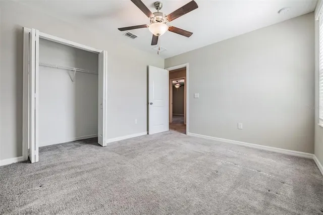 an empty room with closet and a ceiling fan
