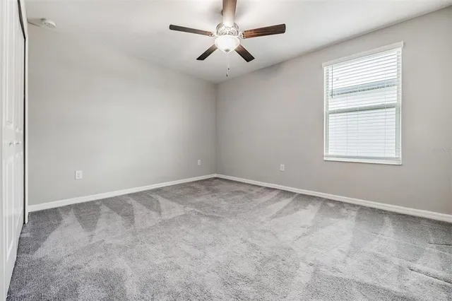 an empty room with a window and a fan