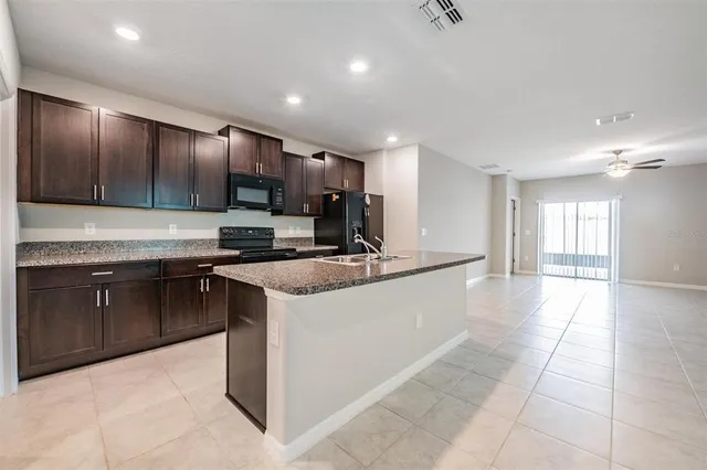 a large kitchen with stainless steel appliances kitchen island granite countertop a sink and cabinets
