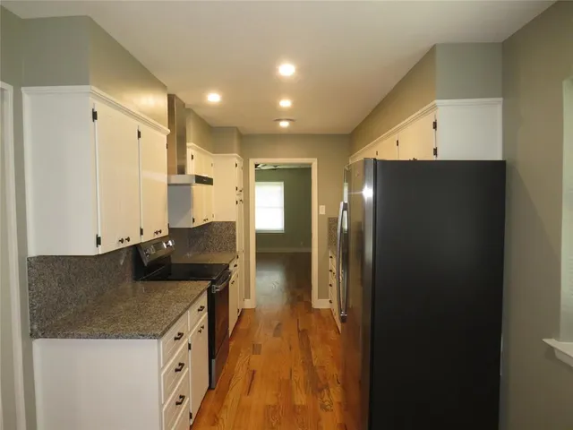 an empty room with wooden floor a ceiling fan a fireplace and windows