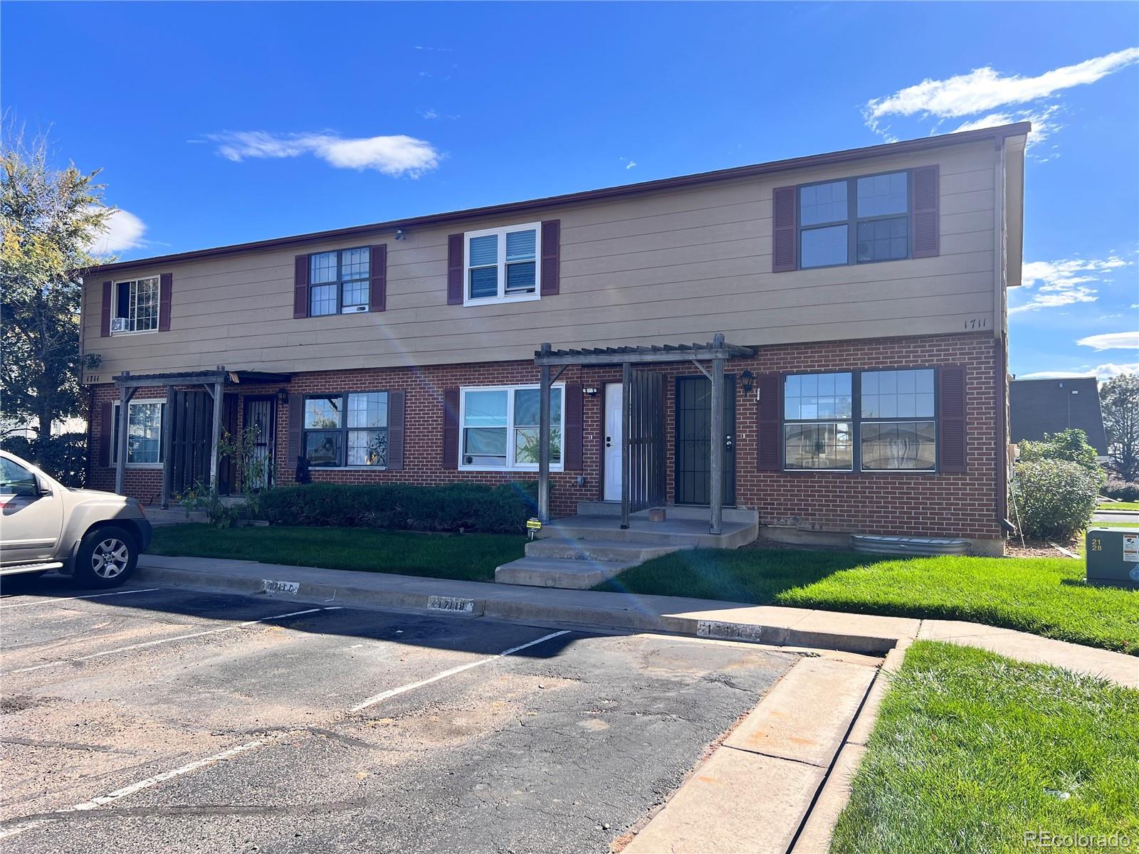 1711 Norfolk Street, Unit D Aurora, CO 80011 - Photo 1 of 16 a front view of a house with a yard and a garage