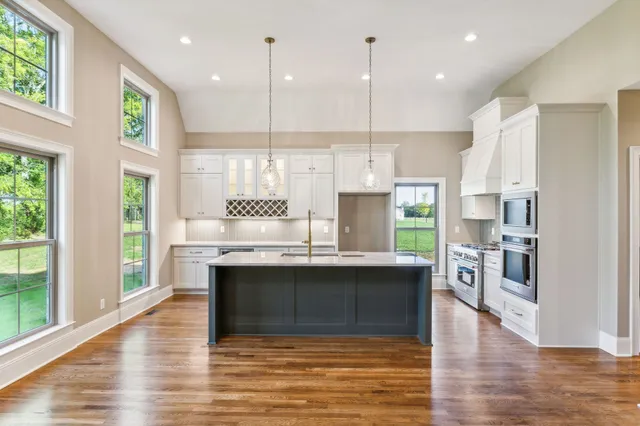 a kitchen with kitchen island granite countertop a sink cabinets and stainless steel appliances