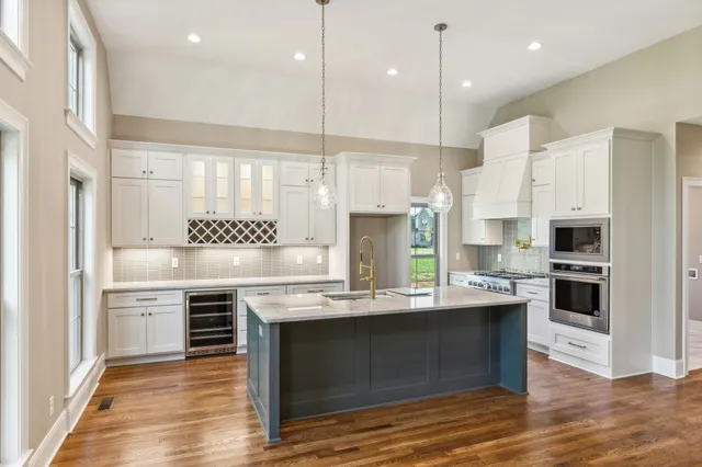a large kitchen with stainless steel appliances granite countertop a stove and a sink with cabinets
