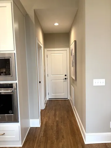 a view of an empty room with wooden floor and windows