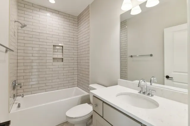 a bathroom with a granite countertop sink a toilet a mirror and shower