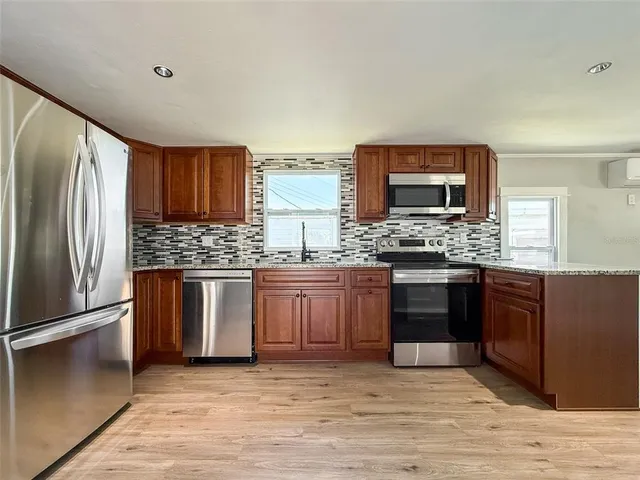 a kitchen with stainless steel appliances kitchen island granite countertop a refrigerator stove and sink