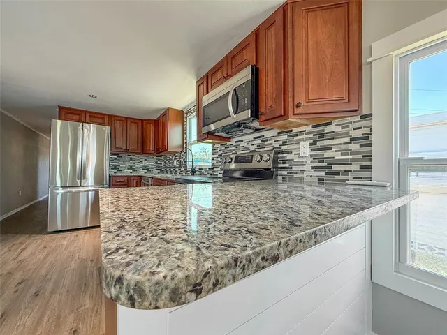 a kitchen with stainless steel appliances granite countertop a stove a sink and a microwave