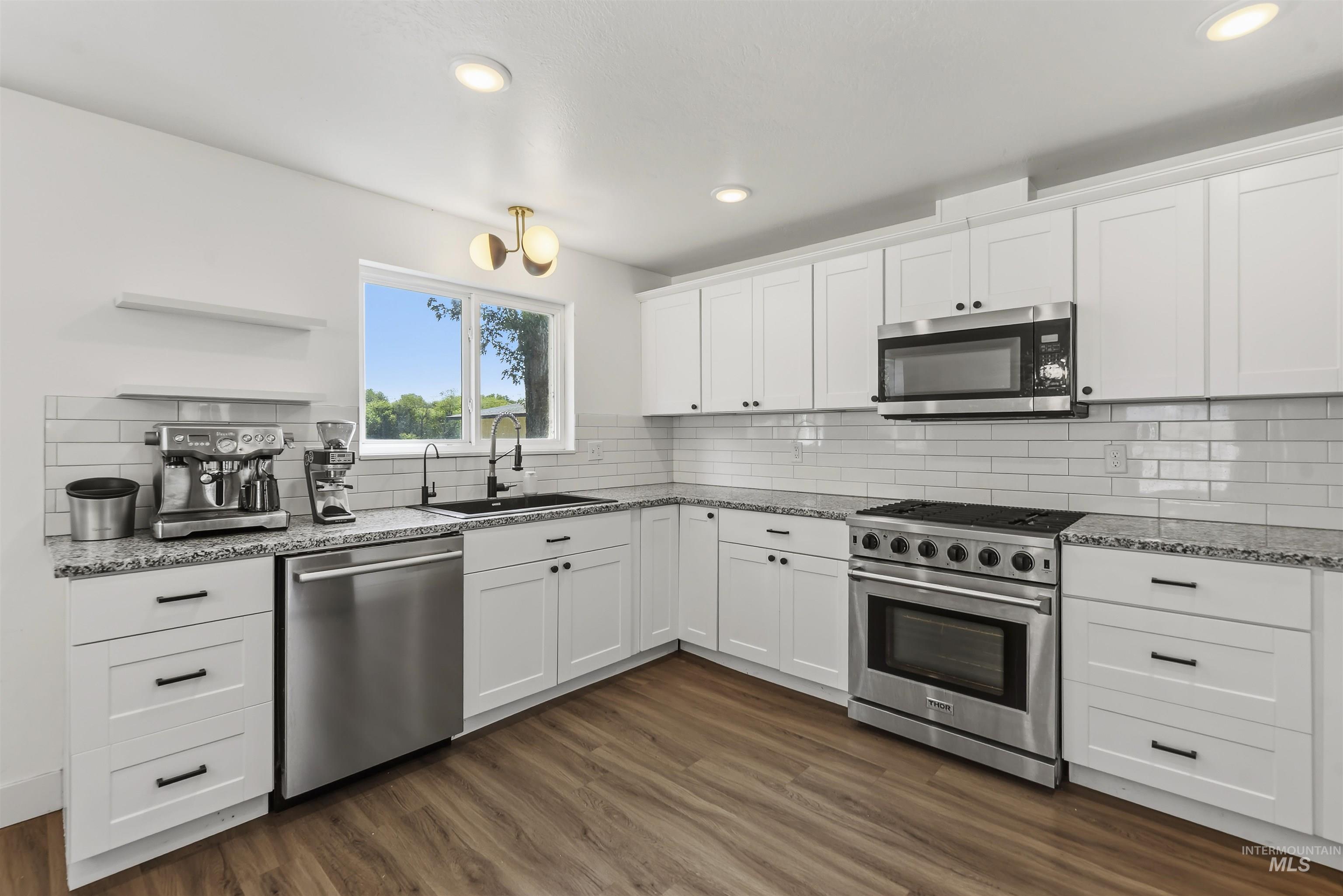 355 East Beacon Light Road Eagle, ID 83616 - Photo 12 of 47 Modern kitchen featuring white shaker cabinetry, stainless steel appliances, granite countertops, and wood-finish flooring