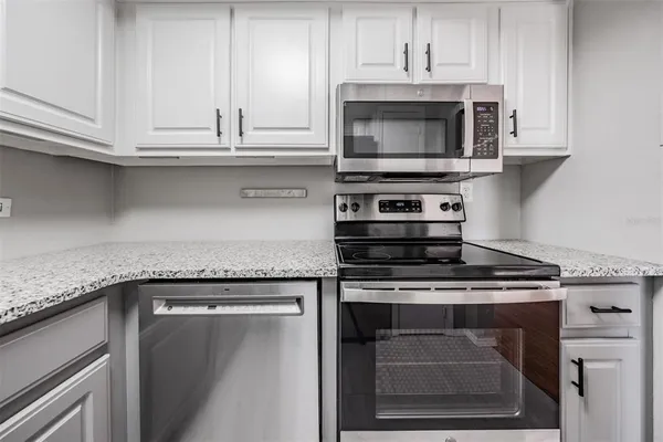 a kitchen with granite countertop white cabinets and stainless steel appliances