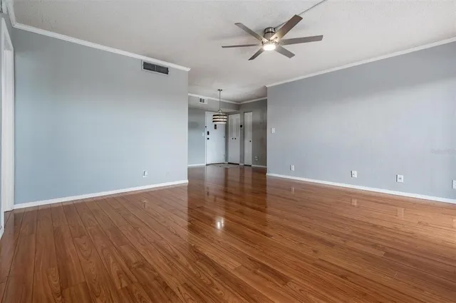 a view of empty room with wooden floor and ceiling fan