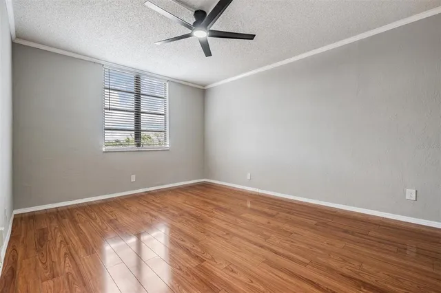 an empty room with wooden floor fan and windows