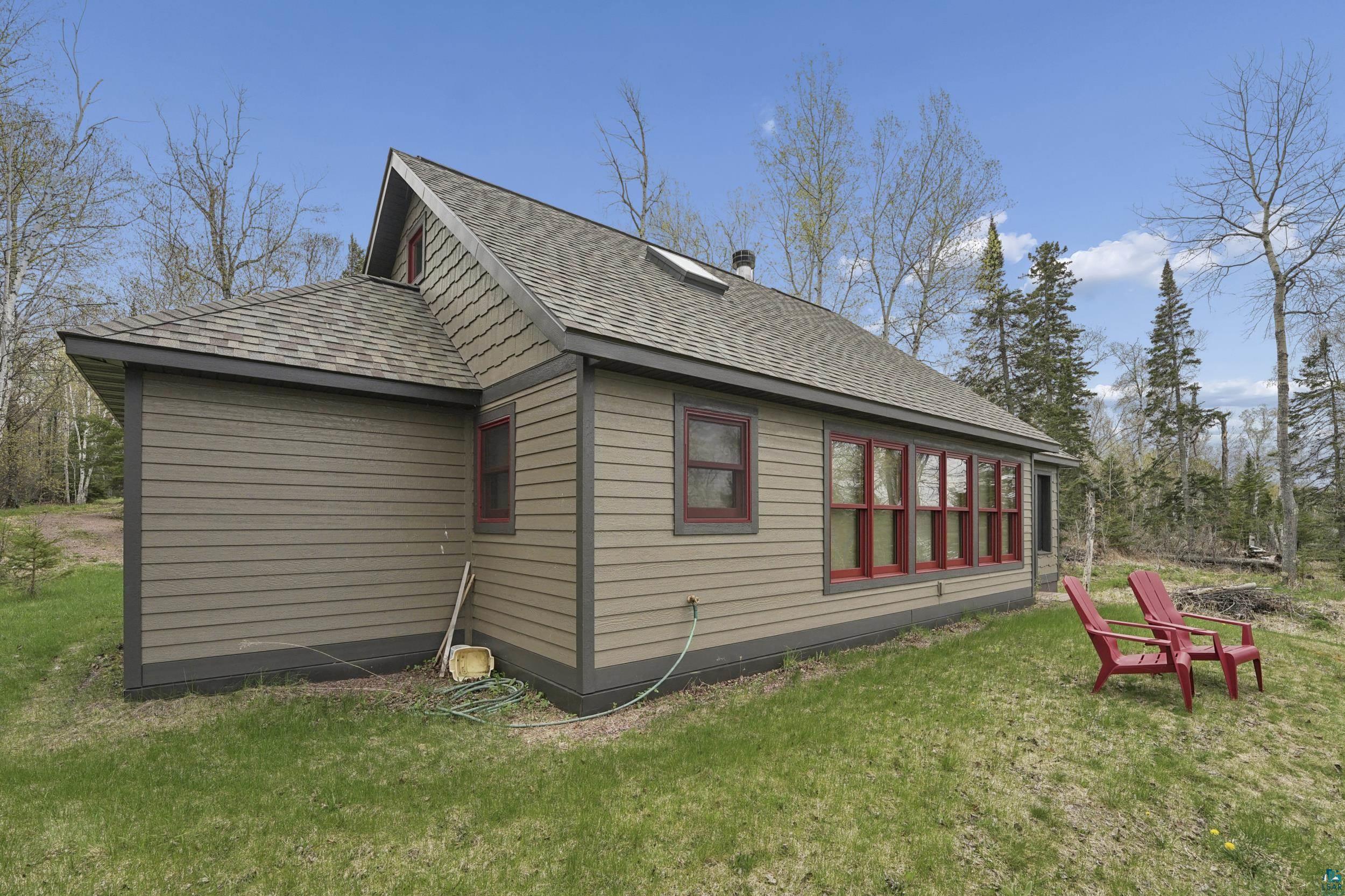 89095 West Romans Point Road Herbster, WI 54844 - Photo 26 of 30 Exterior featuring horizontal siding, dark trim, a gabled roof, and multiple large windows with red frames