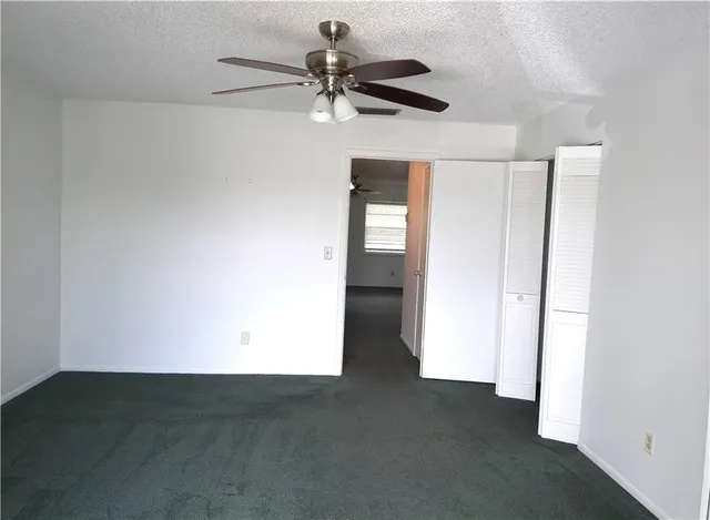 an empty room with a ceiling fan and a window