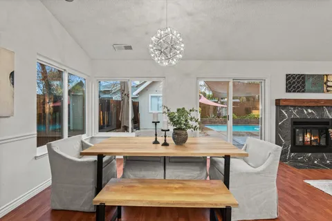 a dining room with wooden floor a chandelier a refrigerator and windows